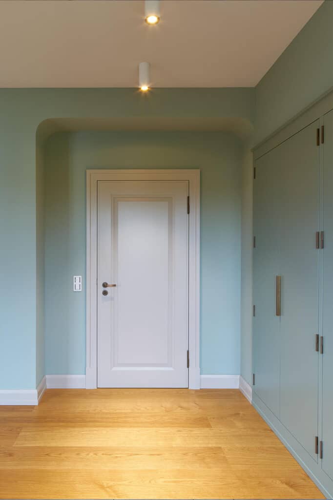 Mintfarbender Raum mit weißer Holztür und Holzfußboden